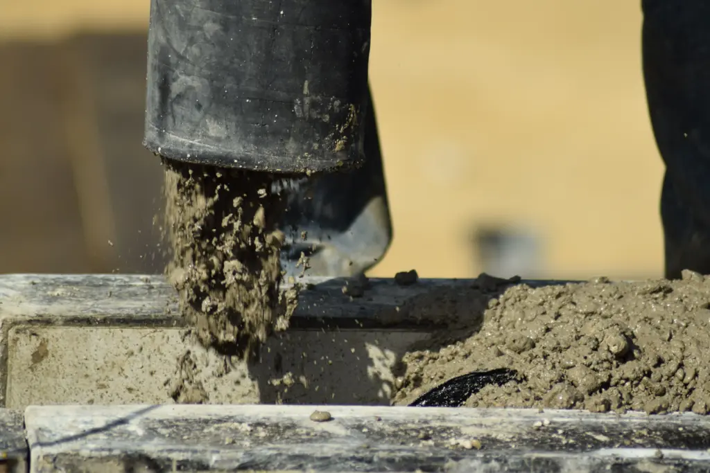 Wet concrete is being poured into formwork during structural wall construction.