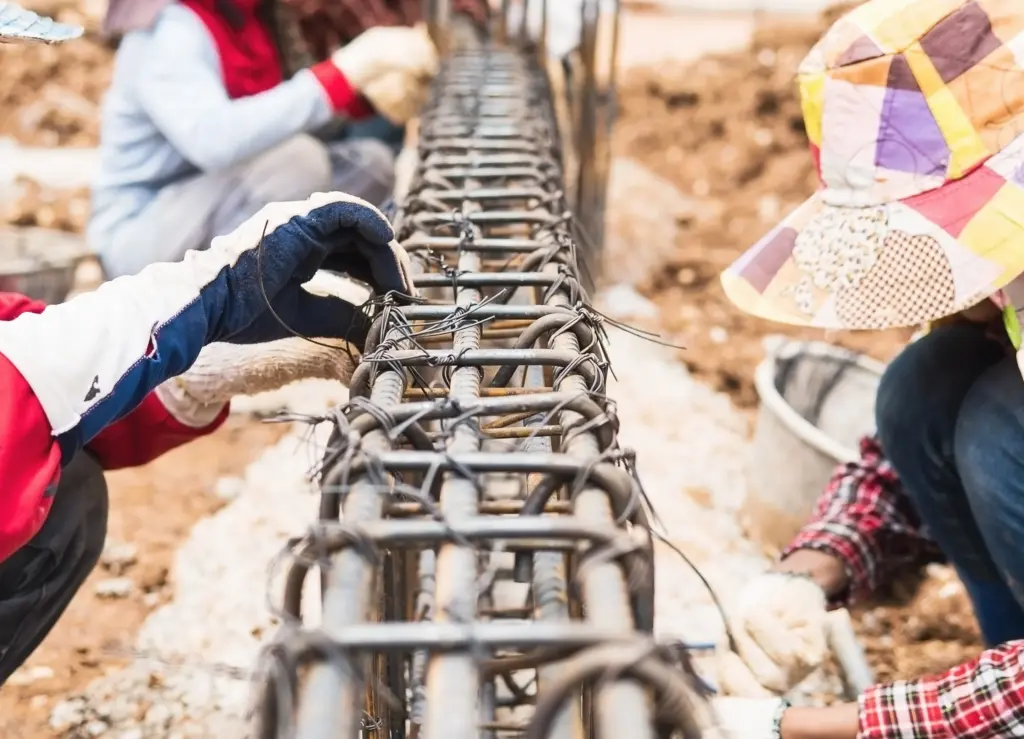 Workers tying steel reinforcement before concrete is placed inside the ICF wall.