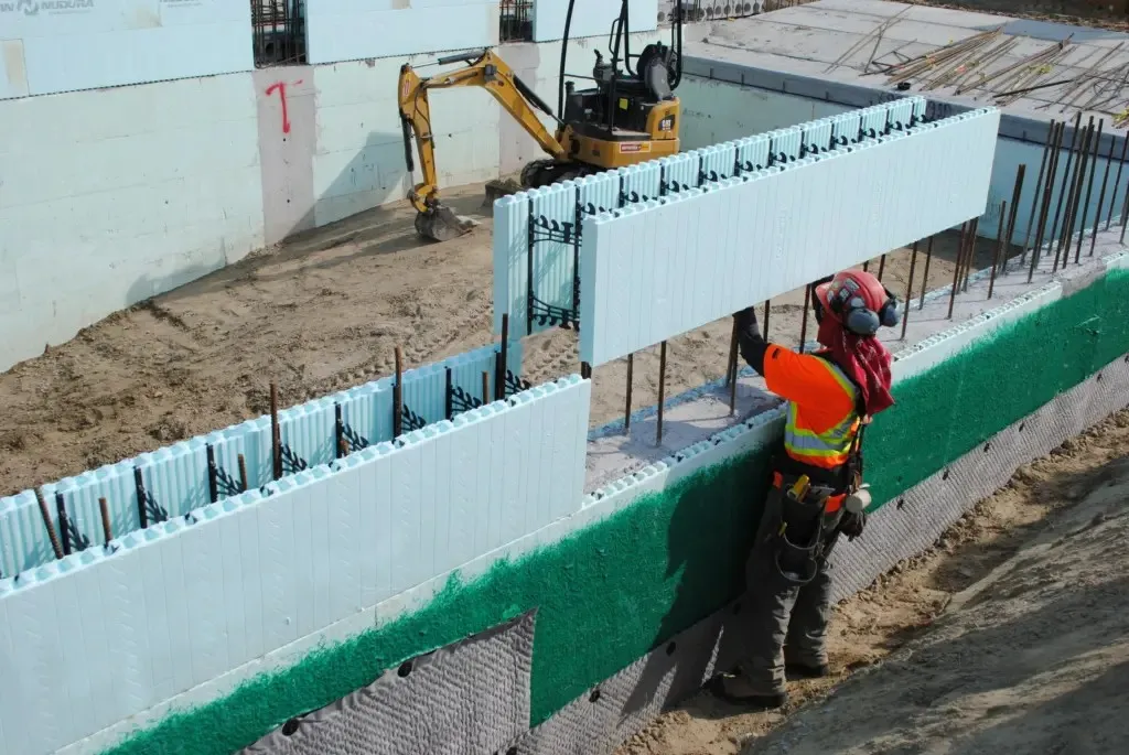 Worker installing reinforced ICF wall forms during construction.